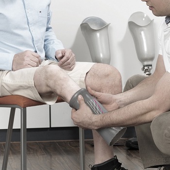 Prosthetist helping a patient remove their liner from their right leg amputated below the knee residual limb