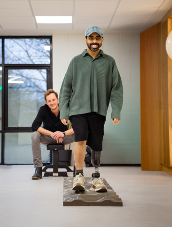 Below-Knee Prosthetic Assessment on Uneven Surface Adult male with below-knee prosthesis walking on uneven surface during clinic assessment, observed by prosthetist.