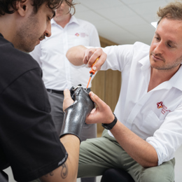 Prosthetist using screwdriver to fine tune a patient's right hand prosthetic socket and terminal device